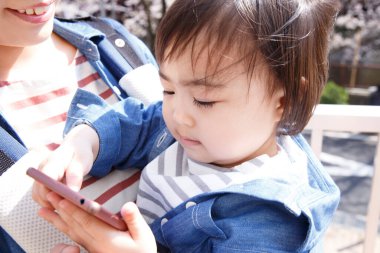 Annesi akıllı telefonlu tatlı bir Japon çocuğunun sokakta portresi.