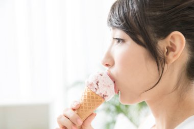 Genç ve güzel Asyalı kadın sabahları dondurma yiyor.