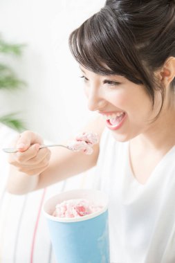 Evde dondurma yiyen genç bir kadının portresi.