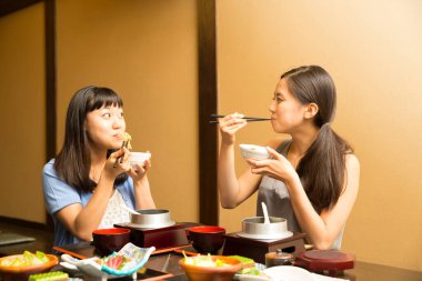 Güzel Asyalı kadınlar restoranda geleneksel Japon yemekleri yiyorlar.