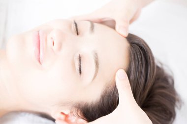 Genç ve güzel Japon kadın spa merkezinde yüz masajından zevk alıyor..