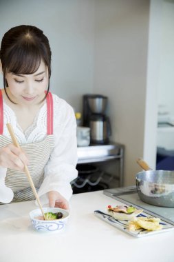 Güzel Asyalı kadın mutfakta yemek yapıyor.