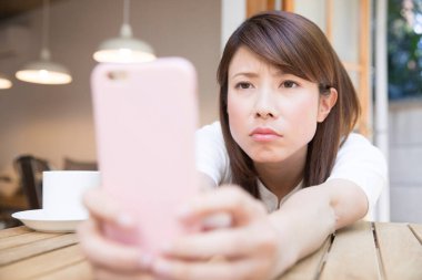 Kafede akıllı telefon kullanan bir kadın.