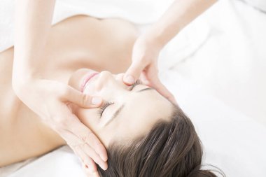 Genç ve güzel Japon kadın spa merkezinde yüz masajından zevk alıyor..