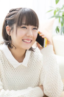 Evde akıllı telefondan konuşan Japon kadının portresi.