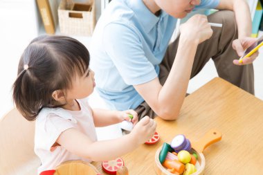 Genç Asyalı kız babası sigara içerken oyun oynuyor. 