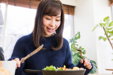 Güzel genç bir kadın Japon restoranında öğle yemeği yiyor.