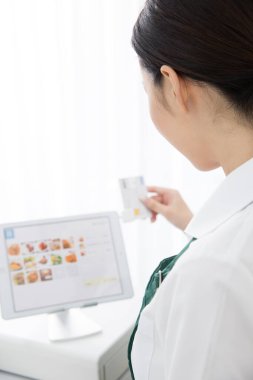 Genç Asyalı kadın ofiste tablet kullanıyor.