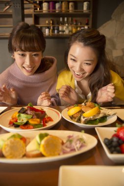 Genç Asyalı bayan arkadaşlar restoranda kahvaltı yapıyorlar..