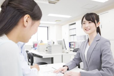 Asyalı kadınlar ofiste konuşuyor.