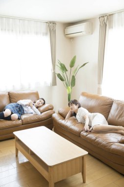 two asian women on sofas at home