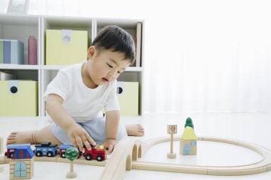 Küçük Asyalı çocuk evde oyuncaklarla oynuyor.