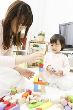 Asyalı anne ve bebek renkli tahta bloklarla oynuyorlar. 