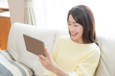 Evde tablet bilgisayar kullanan Asyalı kadın.