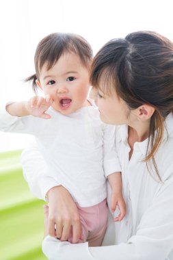 Evdeki oturma odasında genç annesiyle oynayan tatlı bir Japon kızı.