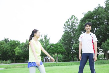 Sportif genç Asyalı çift parkta koşmadan önce geriniyor.