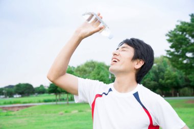 Eğitimden sonra elinde bir şişe su olan genç yakışıklı adam. 