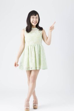 Beyaz arka planda jest yapan yeşil elbiseli Japon kadın. 