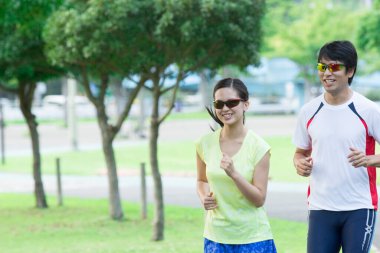 Sportif genç Asyalı çift parkta koşuyor.