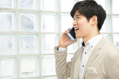 Ofisinde cep telefonu olan genç bir iş adamı.