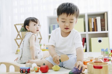 İki Asyalı çocuk evde oyuncaklarla oynuyor.