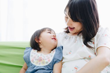 Evdeki oturma odasında annesiyle oynayan tatlı Asyalı küçük kız.