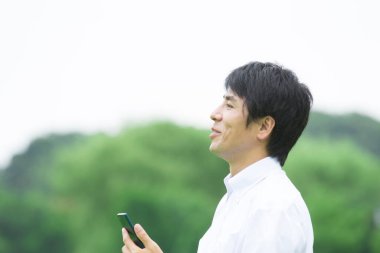 Genç Asyalı adam cep telefonu kullanıyor.