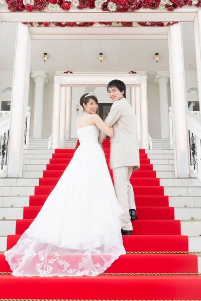 美丽的年轻夫妇穿着红地毯走在楼梯上的倒影 — 图库照片