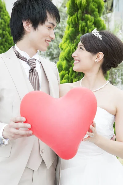 一緒に赤い心を持っている美しい幸せな若い結婚式のカップル — ストック写真