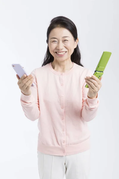 Uśmiechnięta Starsza Kobieta Telefonami Komórkowymi Odizolowana Białym Tle — Zdjęcie stockowe