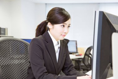 Genç Asyalı iş kadını ofiste bilgisayarla çalışıyor. 