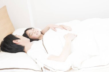 Japon baba ve kızı yatakta birlikte uyuyorlar.
