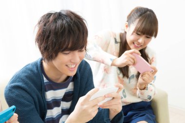 Genç Asyalı çift akıllı telefonlarıyla fotoğraf çekiyor.