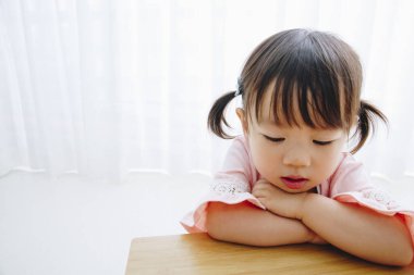 Asyalı küçük kız yerde oturuyor ve düşünüyor. 