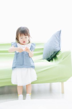 Evdeki oturma odasında oynayan tatlı Asyalı küçük kız.