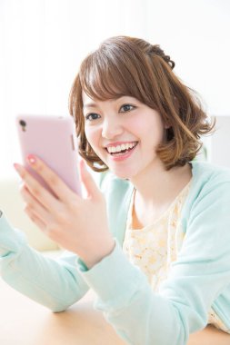 Genç Asyalı kadın akıllı telefon kullanıyor.