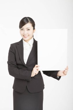 Genç Asyalı kadın beyaz arka planda izole edilmiş boş bir karta uluyor. 