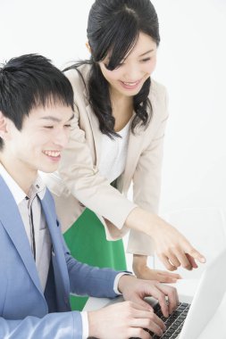 Genç Japon iş adamları ofiste dizüstü bilgisayarla çalışıyorlar.