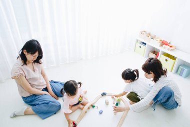 Asyalı anne evde küçük kızlarıyla oynuyor. 