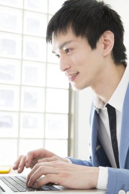 Ofisinde dizüstü bilgisayarda çalışan genç bir adamın portresi.