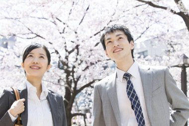 Şehir caddesinde kiraz çiçekleri olan iki Japon iş adamı.