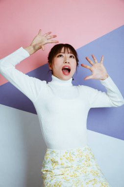 Stüdyoda parlak pembe arka planda poz veren güzel Asyalı kadının portresi.