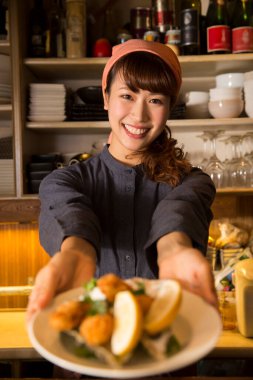 Genç bayan şef restoranda yemek servisi yapıyor.