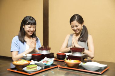 Güzel Asyalı kadınlar restoranda geleneksel Japon yemekleri yiyorlar.