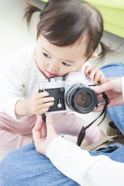 Anne ve küçük kız kamerayla oynuyorlar. 