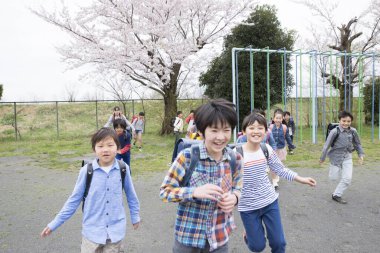 Okul bahçesinde koşan sırt çantalı bir grup Japon çocuk. 