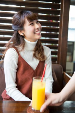 Restoranda portakal suyu içen Asyalı kadın.