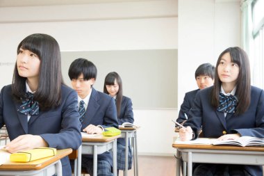 Genç Japon öğrenciler sınıfta okuyor.