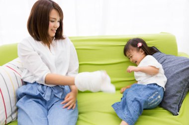 Asyalı anne ve küçük kız evde eğleniyorlar.