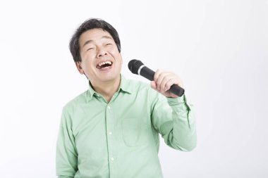 Beyaz arka planda izole edilmiş Asyalı bir adam karaoke söylüyor. 